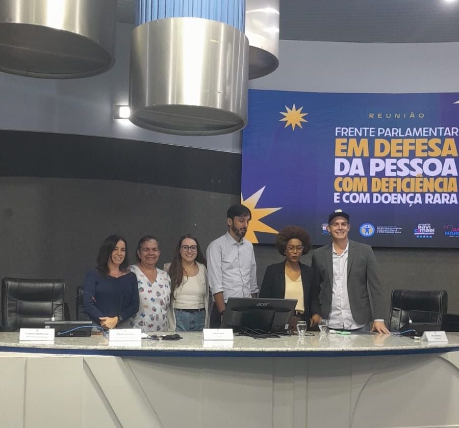 Seis pessoas à mesa do plenário, diante do telão da Frente Parlamentar